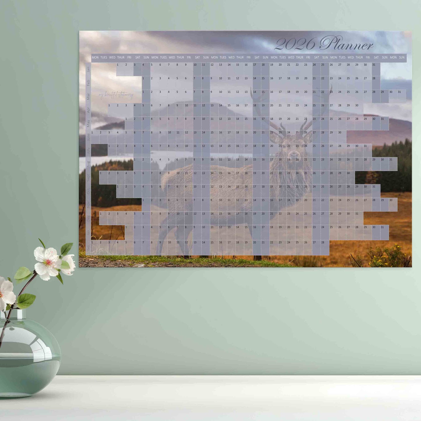 Wall calendar with a scenic design of a deer and mountains.