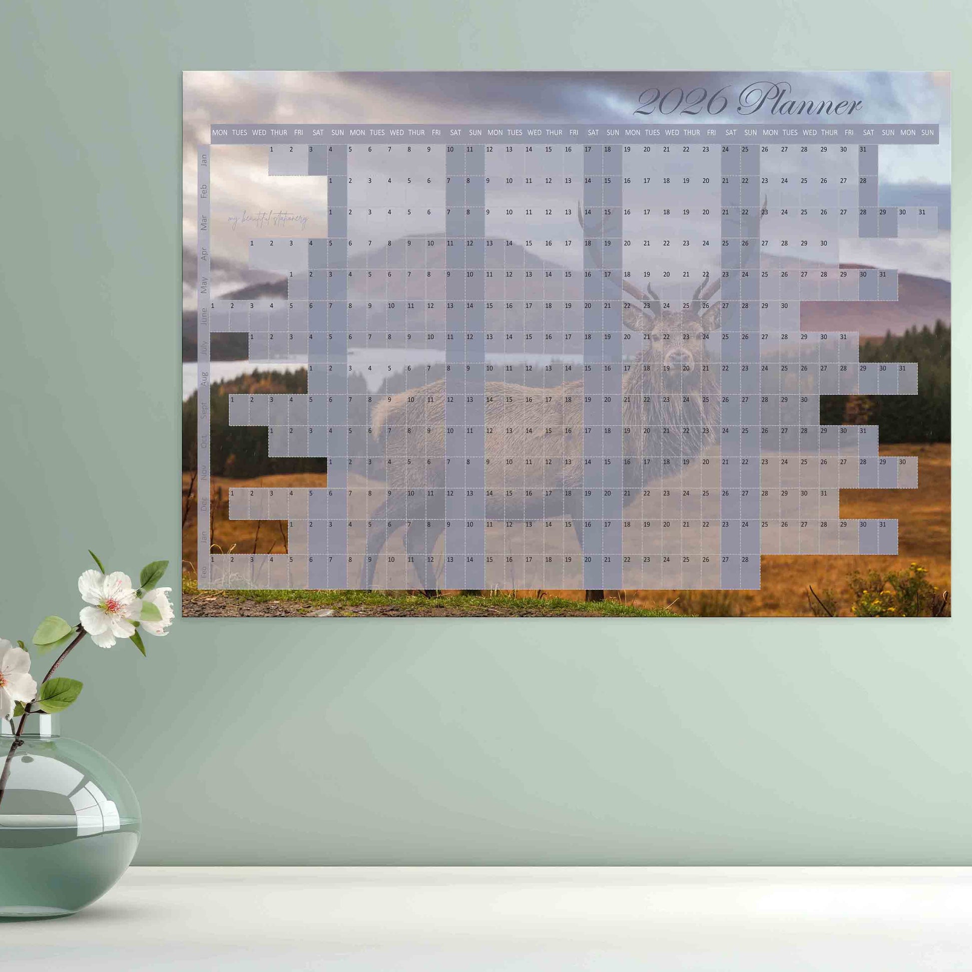 Wall calendar with a scenic design of a deer and mountains.